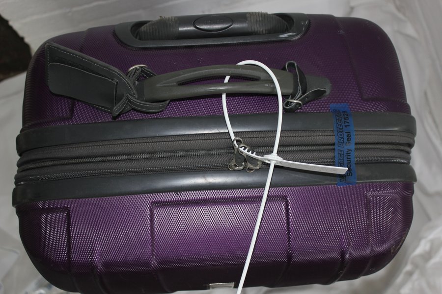 A suitcase sealed with a numbered security tag