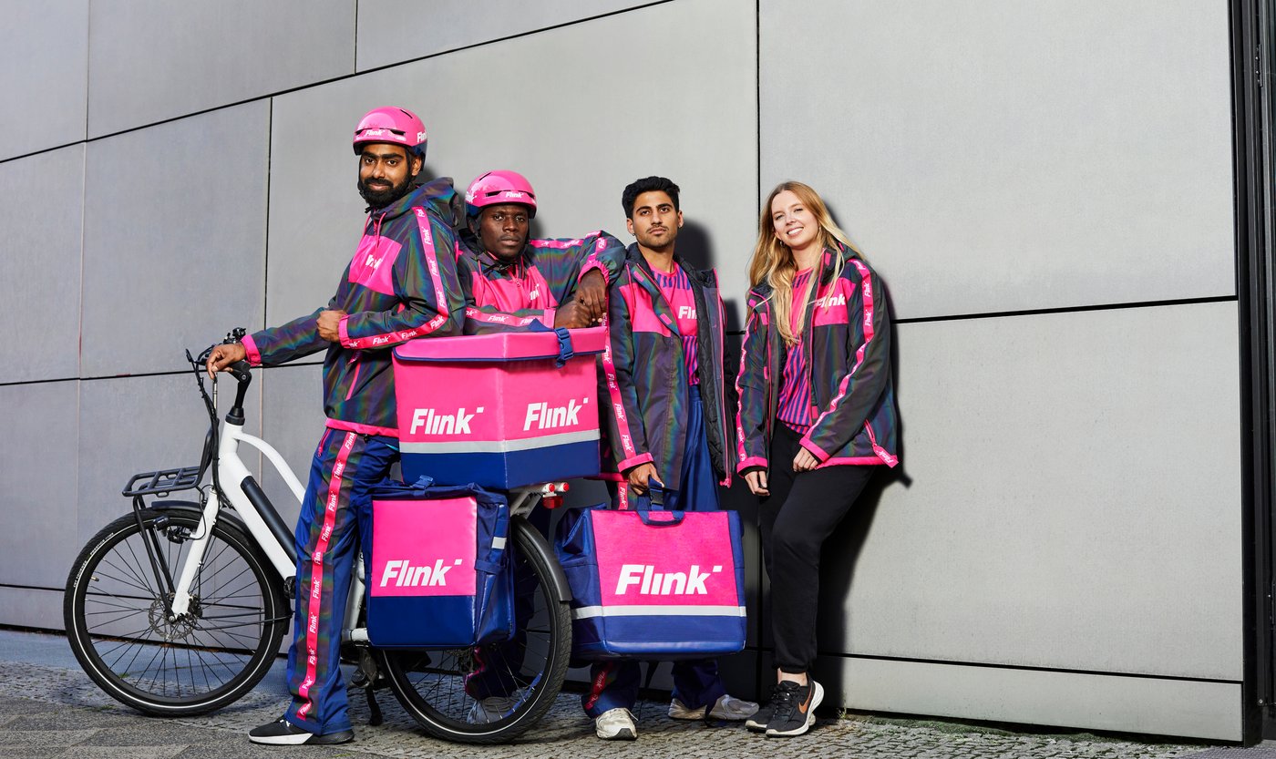 A Flink rider crew in the brand's pink gear with a cargo bike